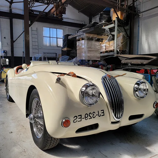 Voiture de sport vintage Jaguar XK120 beige dans un garage encombré à Nanterre en Hauts-de-Seine 92