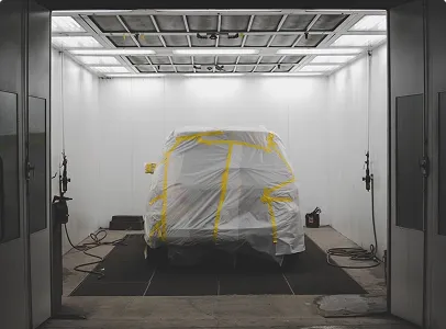 Véhicule emballé sous plastique et ruban adhésif jaune dans une cabine de peinture automobile à Nanterre en Hauts-de-Seine 92