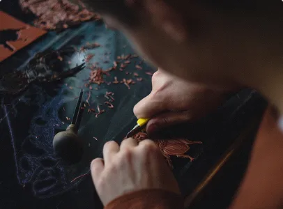 Gros plan sur des mains découpant un dessin de scarabée dans du cuivre, avec des copeaux à Nanterre en Hauts-de-Seine 92