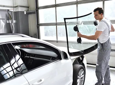 Un mécanicien automobile installe un nouveau pare-brise sur une voiture blanche à Nanterre en Hauts-de-Seine 92