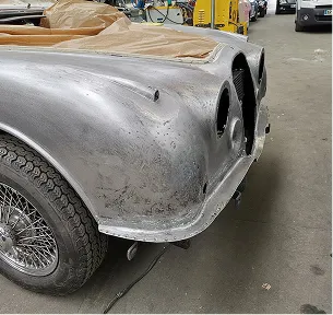 Arrière d'une voiture classique argentée en cours de restauration, avec un pneu et une jante à Nanterre en Hauts-de-Seine 92