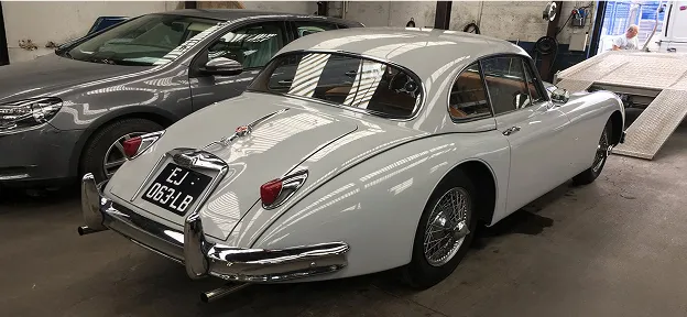 Jaguar XK150 coupé blanc et Volkswagen grise garées dans un garage à Nanterre en Hauts-de-Seine 92