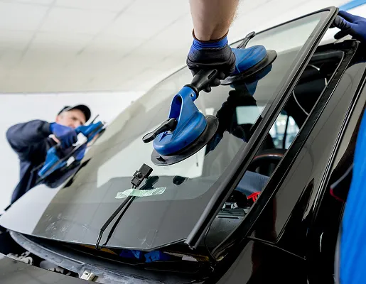 Deux techniciens installent un pare-brise de voiture avec des ventouses à Nanterre en Hauts-de-Seine 92