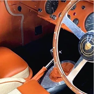 Intérieur marron et crème d'une vieille voiture de sport Jaguar, avec tableau de bord et volant en bois à Nanterre en Hauts-de-Seine 92