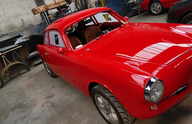 Voiture de sport rouge vintage dans un garage, intérieur marron, détails chromés à Nanterre en Hauts-de-Seine 92