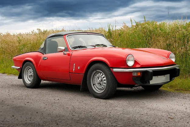 Voiture de sport décapotable rouge, une Triumph Spitfire, sur une route de campagne à Nanterre en Hauts-de-Seine 92